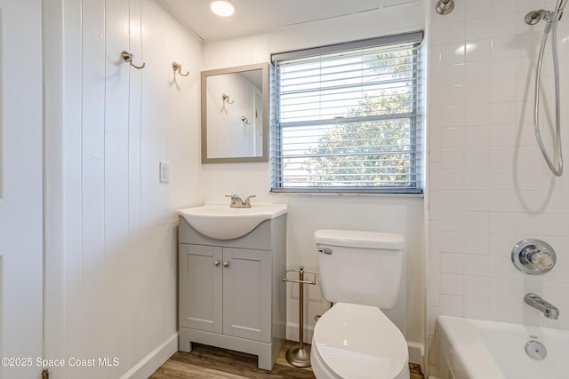 full bathroom with hardwood / wood-style flooring, vanity, tiled shower / bath combo, and toilet