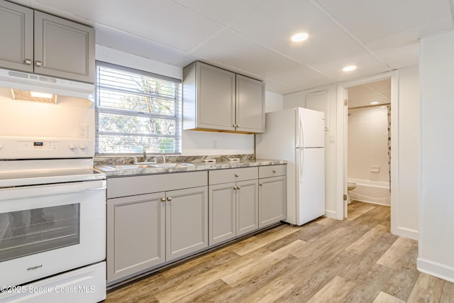 kitchen with light stone countertops, gray cabinetry, white appliances, sink, and light hardwood / wood-style flooring