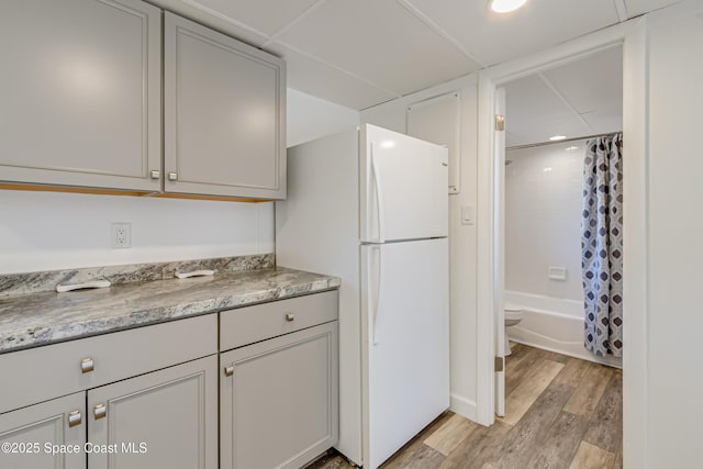 kitchen featuring light wood-type flooring, white refrigerator, and gray cabinets