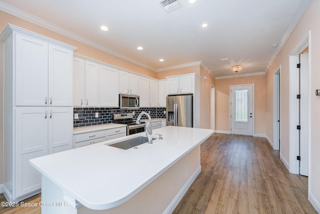 kitchen with sink, backsplash, an island with sink, white cabinets, and appliances with stainless steel finishes