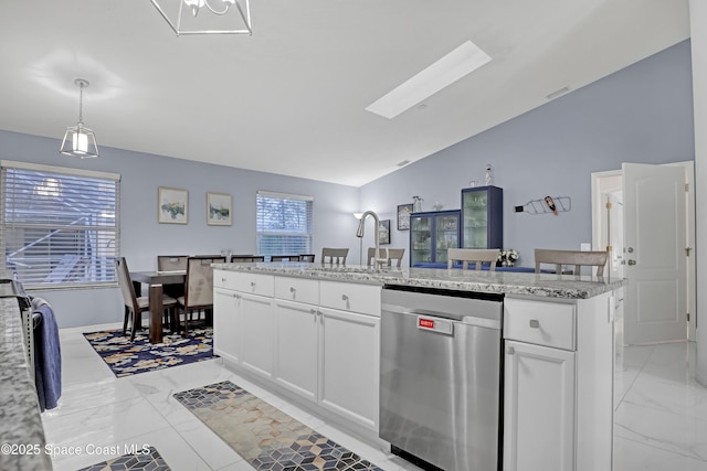 kitchen with white cabinetry, decorative light fixtures, a center island with sink, dishwasher, and vaulted ceiling with skylight