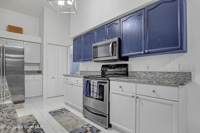 kitchen featuring blue cabinets, light stone counters, white cabinets, and appliances with stainless steel finishes