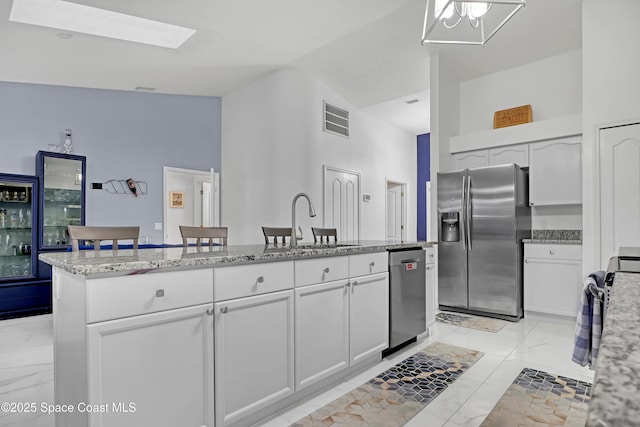 kitchen with stainless steel appliances, a kitchen island, sink, and white cabinets