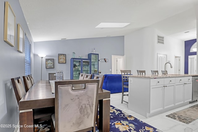 dining space featuring lofted ceiling with skylight and sink