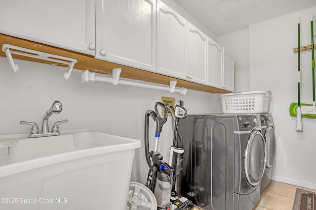 washroom with separate washer and dryer, light tile patterned floors, sink, and cabinets