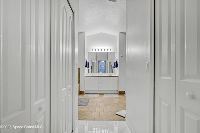 bathroom featuring vanity, vaulted ceiling, tile patterned floors, and a textured ceiling