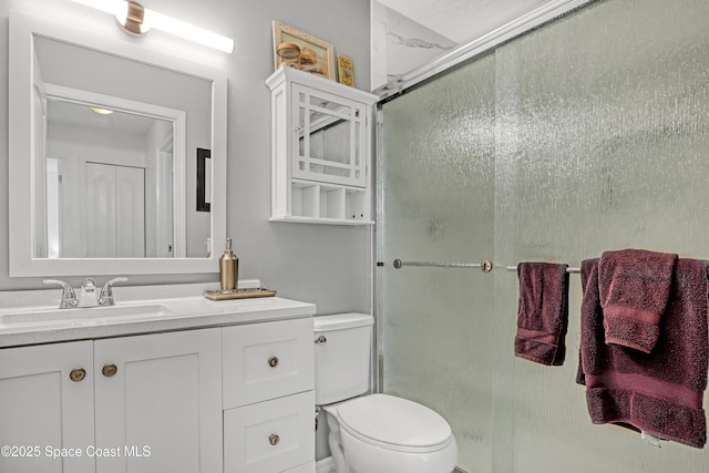 bathroom featuring vanity, a shower with shower door, and toilet