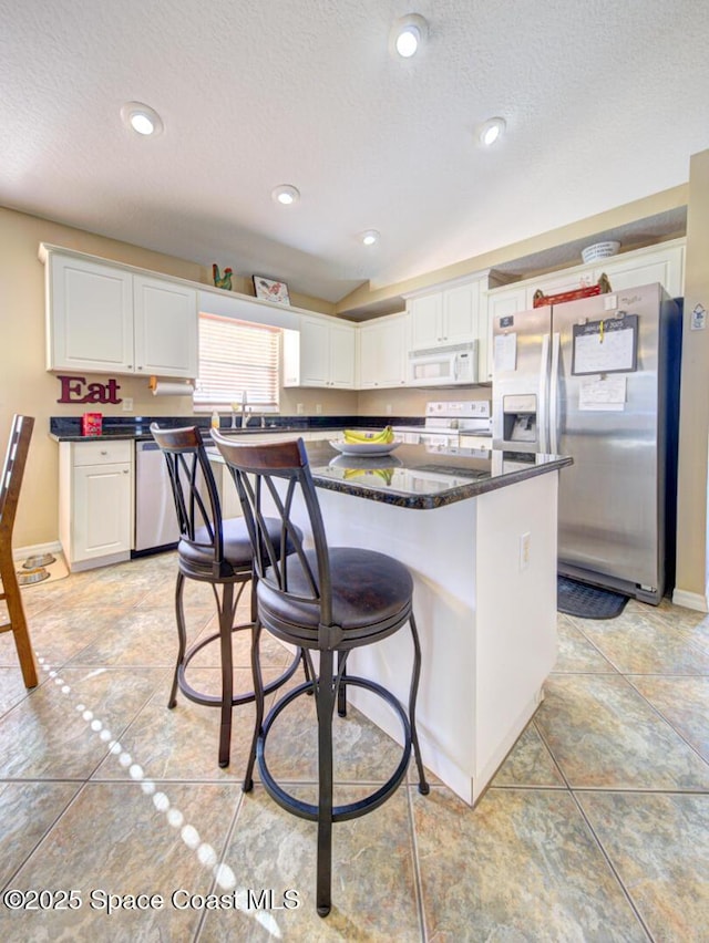 kitchen featuring a center island, stainless steel appliances, white cabinetry, and sink