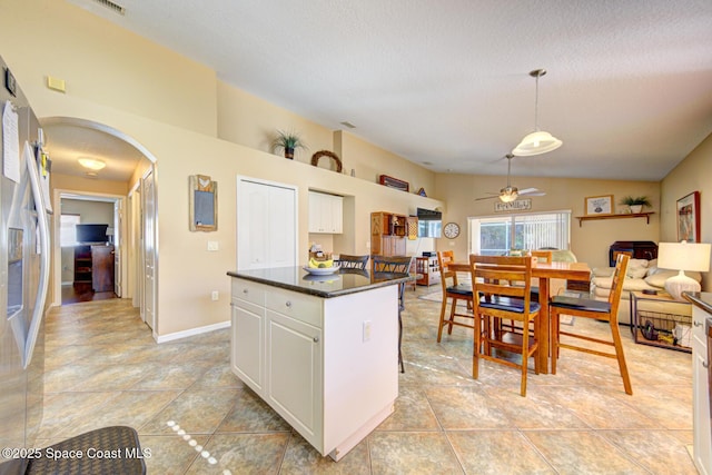 kitchen featuring ceiling fan, a center island, pendant lighting, vaulted ceiling, and white cabinets