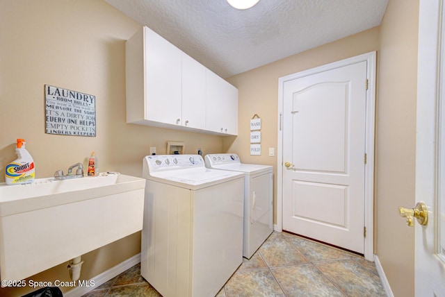 clothes washing area with washing machine and clothes dryer, sink, cabinets, a textured ceiling, and light tile patterned flooring