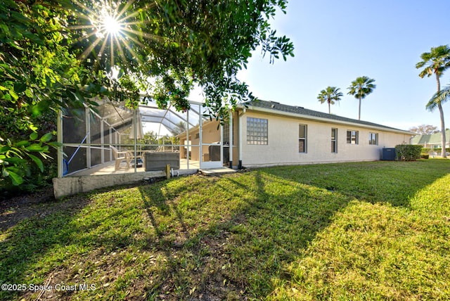 rear view of house featuring glass enclosure, a yard, a patio, and central air condition unit