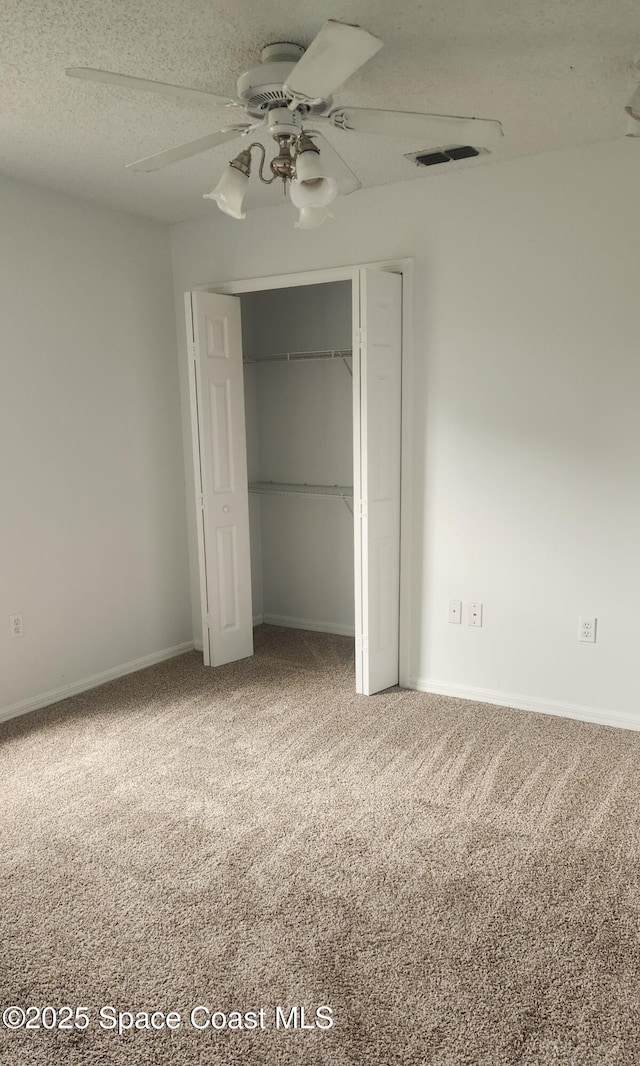 unfurnished bedroom with carpet flooring, ceiling fan, a textured ceiling, and a closet