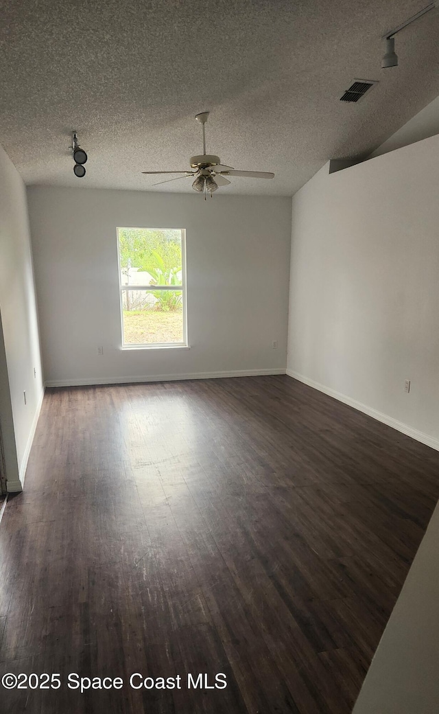 empty room featuring a textured ceiling, ceiling fan, and dark wood-type flooring