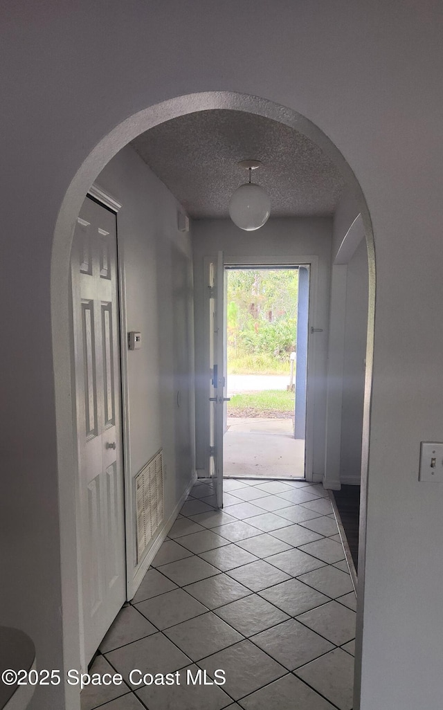 doorway to outside featuring light tile patterned flooring and a textured ceiling