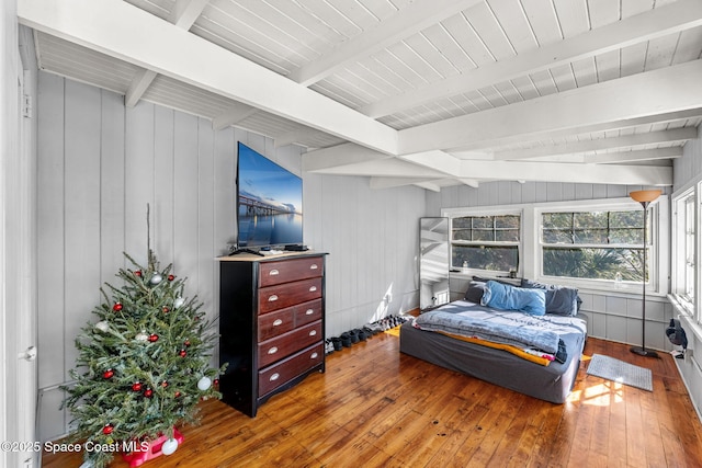 bedroom featuring beam ceiling, wooden walls, and wood-type flooring