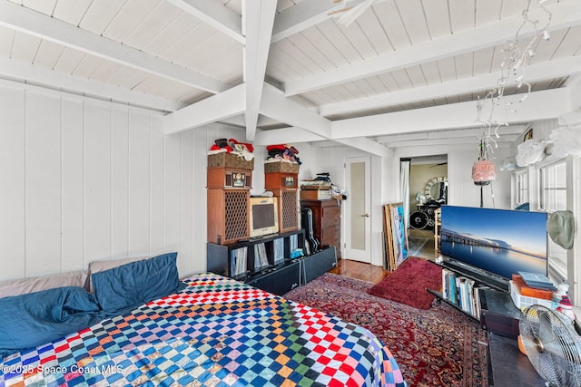 bedroom featuring wooden walls, beamed ceiling, and hardwood / wood-style flooring