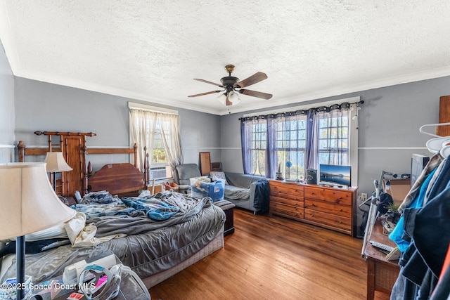 bedroom featuring hardwood / wood-style flooring, ceiling fan, crown molding, and a textured ceiling