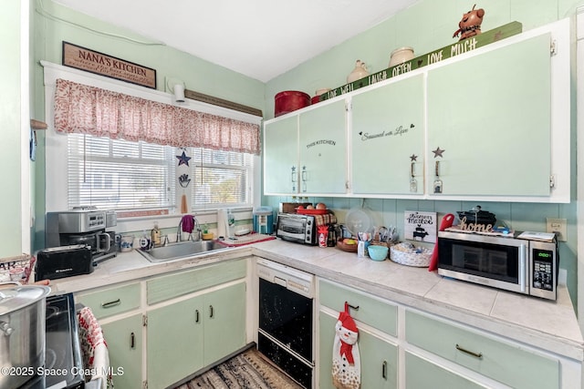 kitchen featuring black dishwasher, tile countertops, and sink