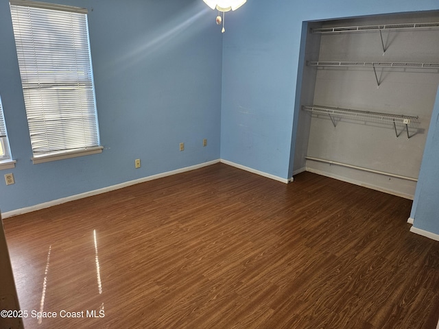 unfurnished bedroom with multiple windows, dark hardwood / wood-style floors, and a closet