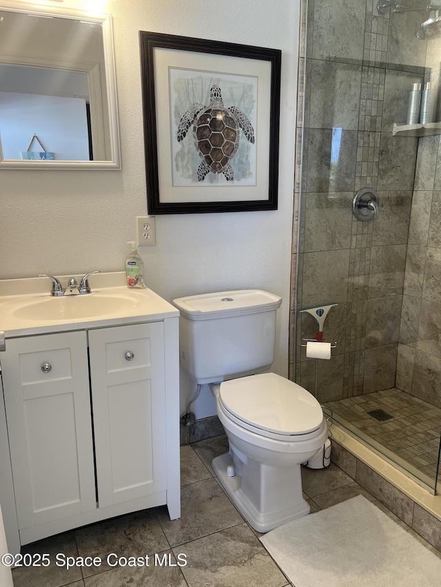 bathroom featuring a tile shower, vanity, and toilet