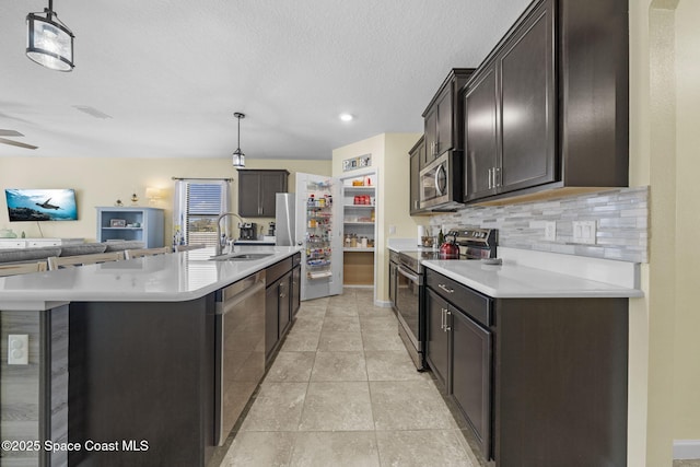 kitchen with decorative light fixtures, dark brown cabinetry, sink, and appliances with stainless steel finishes