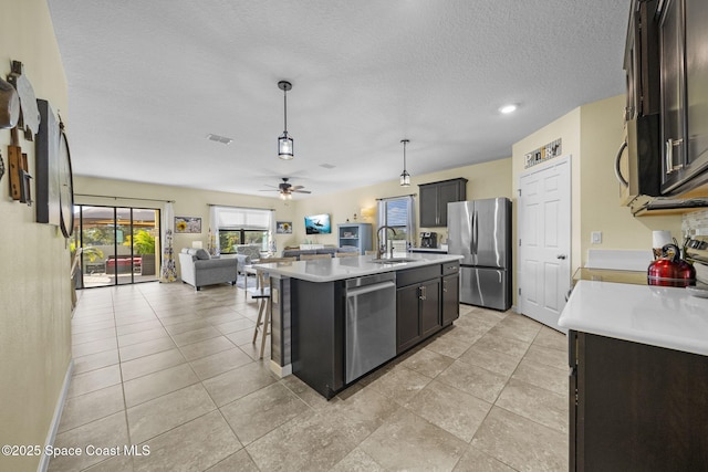 kitchen featuring pendant lighting, a center island with sink, sink, ceiling fan, and appliances with stainless steel finishes