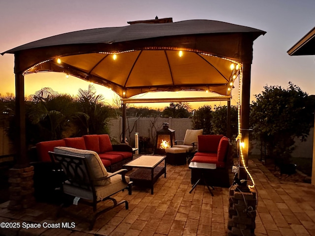 patio terrace at dusk featuring a gazebo and an outdoor living space with a fireplace