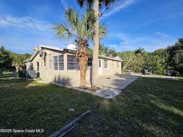 view of side of home with a yard, a patio, and central air condition unit