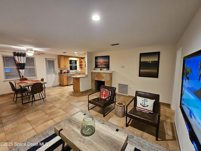 living room featuring a fireplace, light tile patterned floors, and ceiling fan