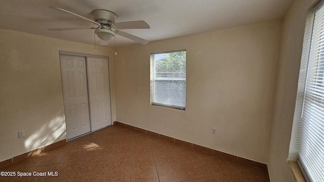 unfurnished bedroom featuring ceiling fan, dark tile patterned floors, and a closet