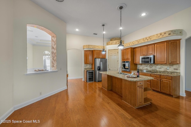 kitchen with tasteful backsplash, a kitchen island with sink, hanging light fixtures, and stainless steel appliances