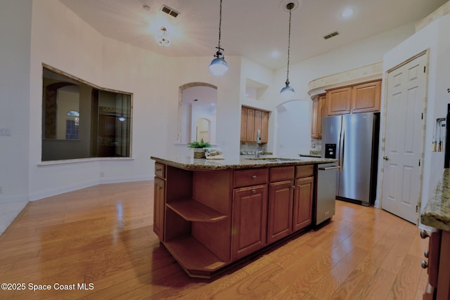 kitchen featuring sink, light hardwood / wood-style flooring, decorative light fixtures, a kitchen island, and stainless steel appliances