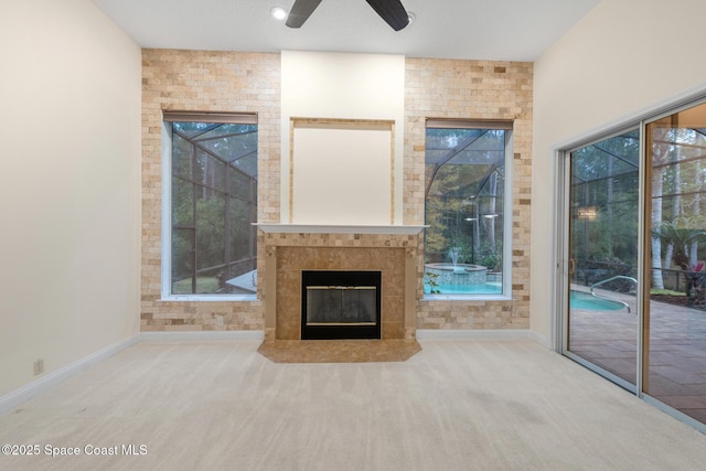 unfurnished living room with carpet, ceiling fan, and a tile fireplace