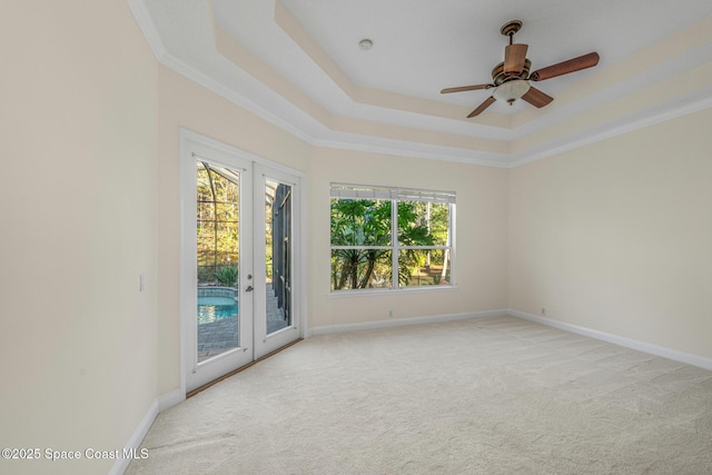 unfurnished room featuring a tray ceiling, light carpet, french doors, and ceiling fan