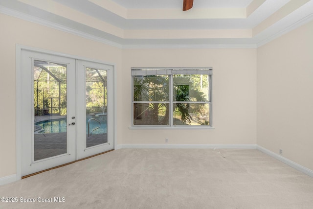 unfurnished room featuring crown molding, light carpet, a tray ceiling, and french doors