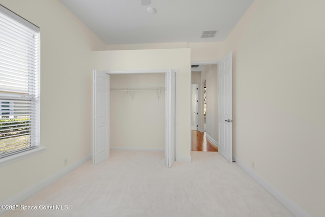 unfurnished bedroom featuring light carpet and a closet