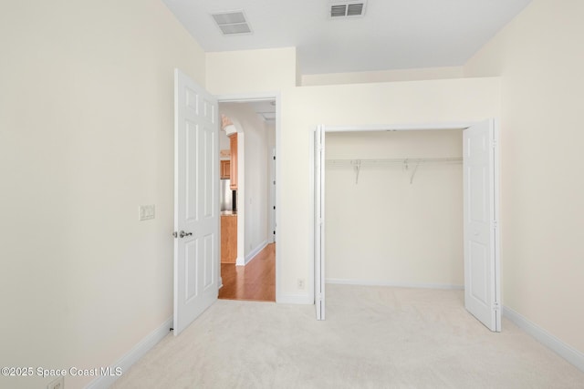 unfurnished bedroom with light colored carpet and a closet