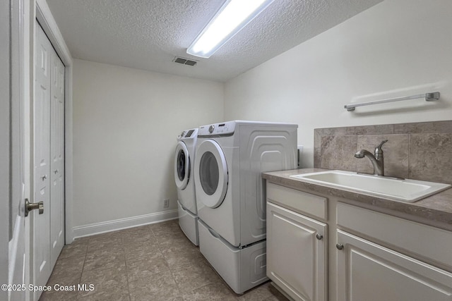 washroom featuring washing machine and dryer, sink, cabinets, and a textured ceiling