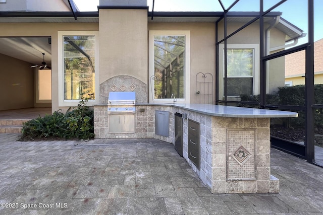 view of patio / terrace featuring ceiling fan, a wet bar, exterior kitchen, and grilling area