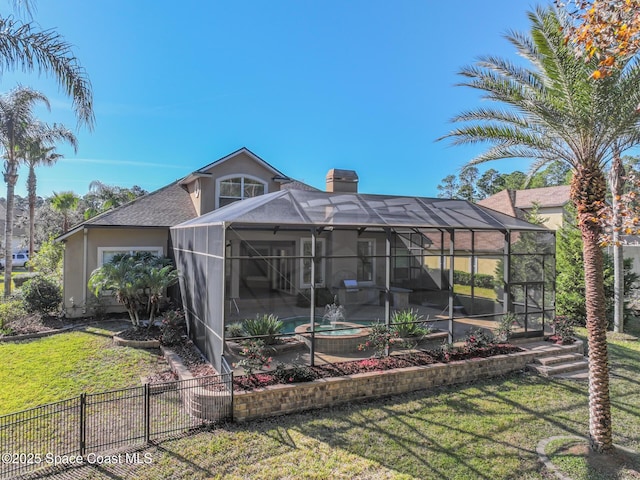 back of house with a yard, glass enclosure, and a pool with hot tub