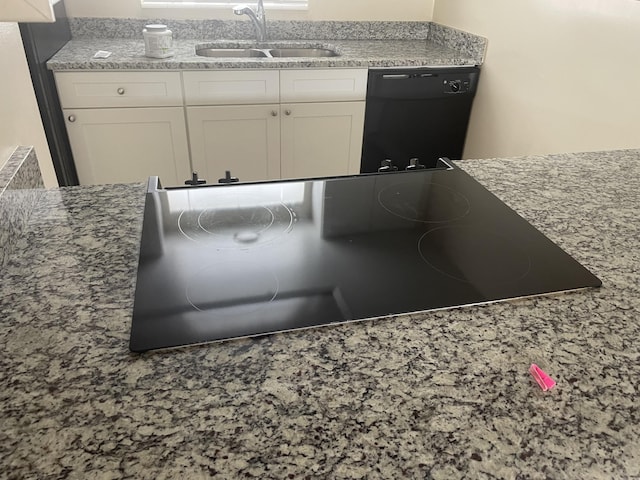 kitchen featuring light stone countertops, sink, white cabinetry, and black appliances