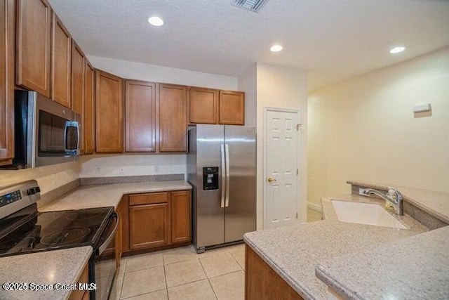 kitchen with light stone counters, sink, light tile patterned flooring, and appliances with stainless steel finishes