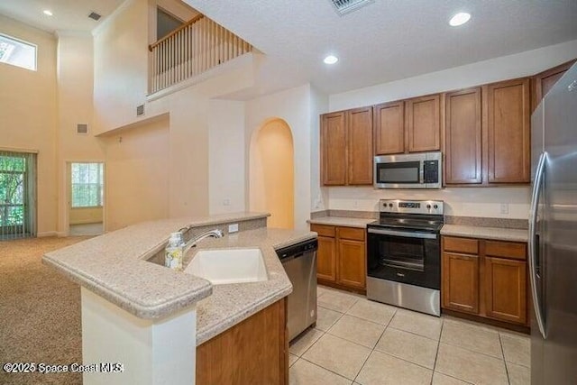 kitchen featuring appliances with stainless steel finishes, light tile patterned floors, a wealth of natural light, and sink