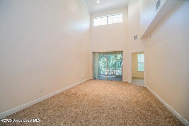 unfurnished living room with a high ceiling, carpet floors, and a wealth of natural light