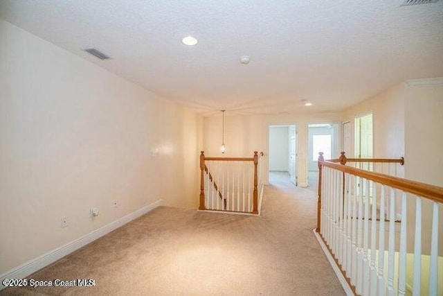 unfurnished room featuring a textured ceiling and light carpet