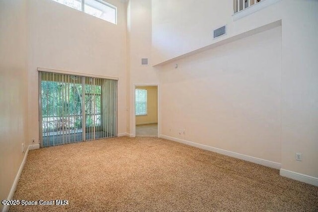 empty room featuring carpet flooring and a towering ceiling