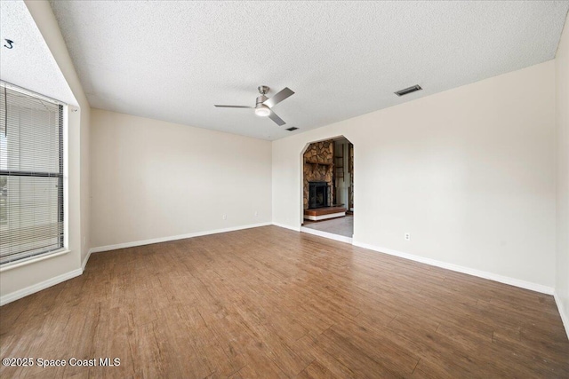 unfurnished living room with a fireplace, wood-type flooring, a textured ceiling, and ceiling fan