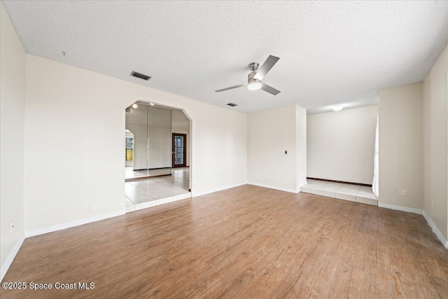 empty room featuring ceiling fan, light hardwood / wood-style floors, and a textured ceiling