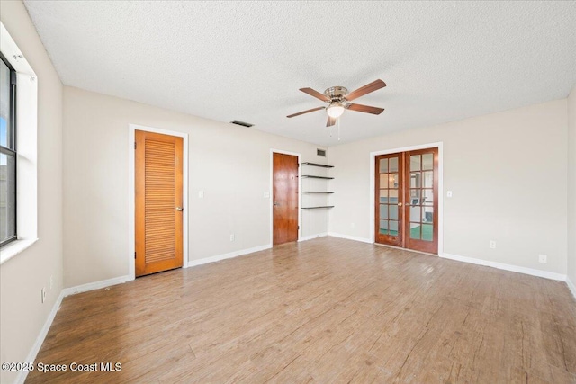 spare room featuring light wood-type flooring, french doors, a textured ceiling, and ceiling fan