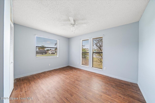 spare room with a textured ceiling, ceiling fan, and dark wood-type flooring